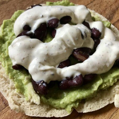 tartine de pain pita à l'avocat, aux haricots rouges et à la crème épicée